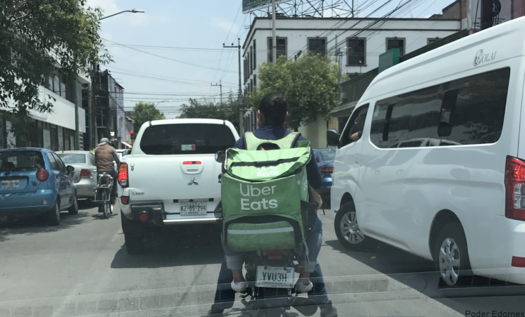 Nótese van dos personas en la moto, que si tiene placa y llevan a hombros la mochila de Uber Eats.